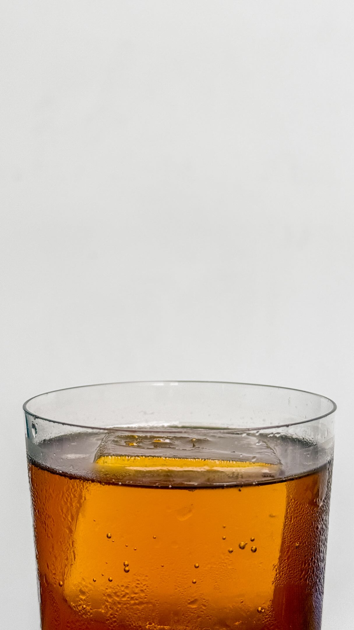 Pahar înalt cu coffee soda chihlimbariu pe fundal alb cald